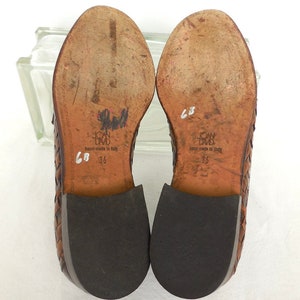 May include: Brown leather woven shoes with black soles. The shoes have the text "John David" and "hand-made in Italy" on the soles. The size is marked as "36" and "68" on the soles.