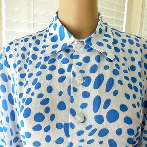 May include: White shirt with a blue polka dot pattern. The shirt features a classic collar and buttoned cuffs. The buttons are white and the fabric appears to be lightweight. The shirt is a classic design.