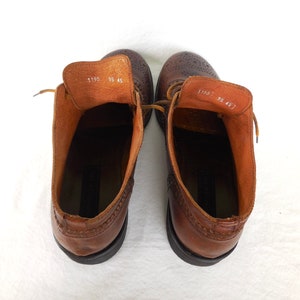 Pode incluir: Um par de botas de tornozelo de couro marrom com design brogue. As botas t&ecirc;m cadar&ccedil;os e bico redondo. O tamanho est&aacute; marcado como 9,5 e 45.