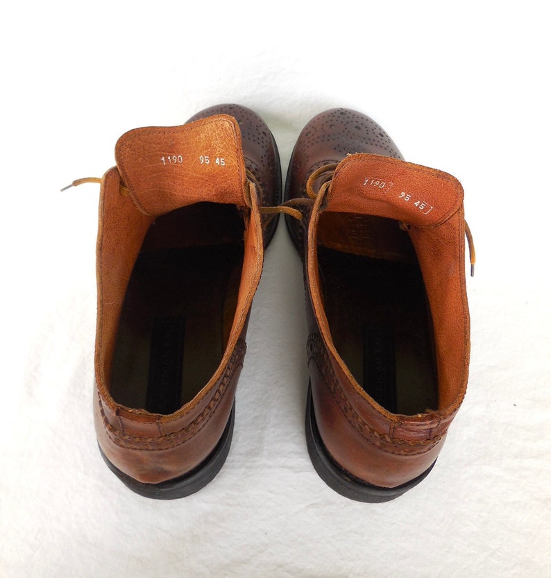 Pode incluir: Um par de botas de tornozelo de couro marrom com design brogue. As botas t&ecirc;m cadar&ccedil;os e bico redondo. O tamanho est&aacute; marcado como 9,5 e 45.