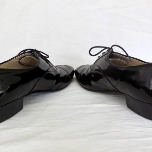 Puede incluir: Par de zapatos negros de charol con tac&oacute;n bajo y cierre de cordones. Los zapatos tienen un acabado brillante y un dise&ntilde;o cl&aacute;sico, adecuado para diversas ocasiones. Los tacones miden aproximadamente 2,5 cm.