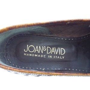 May include: Close-up of the inside of a brown leather loafer with a gold embossed label that reads "Joan & David Handmade in Italy."