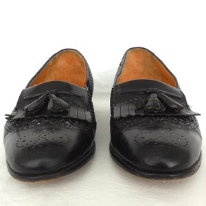 May include: A pair of black leather tassel loafers with a woven pattern and perforated detailing.