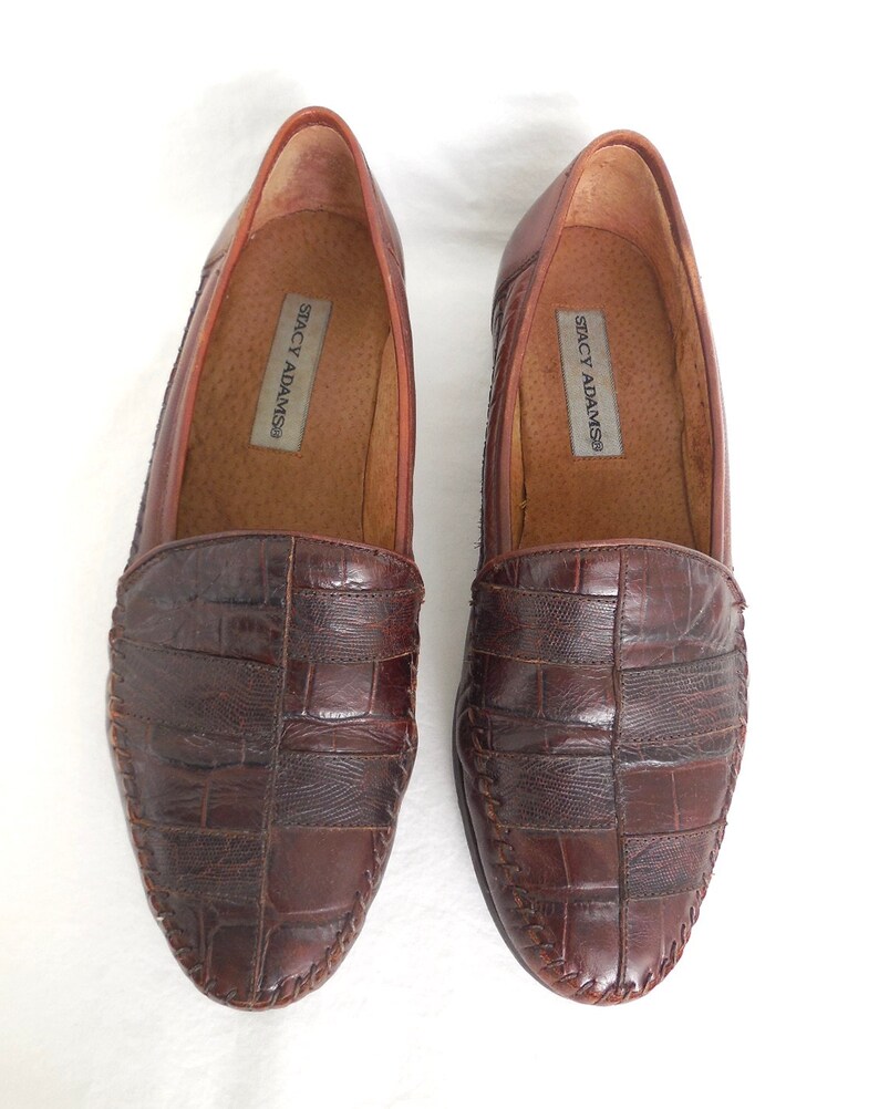 K&ouml;nnte beinhalten: Ein Paar braune Lederschuhe mit Kroko-Pr&auml;gung. Die Schuhe sind Slipper und von der Marke Stacy Adams.