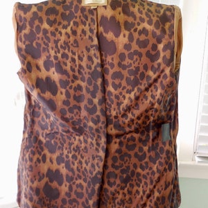 May include: A brown leather jacket with a leopard print lining. The jacket has a zipper closure and a collar.