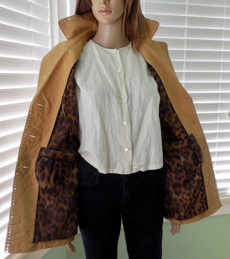 May include: A tan leather jacket with a leopard print lining. The jacket has a button closure and pockets.