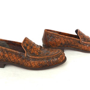 May include: A pair of brown leather woven loafers. The loafers have a woven pattern and a pointed toe.