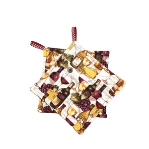 May include: Two white fabric pot holders with red trim and a wine bottle and grape design.