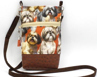 Könnte beinhalten: Umhängetasche mit einem sich wiederholenden Muster von Shih Tzu-Hunden auf orangefarbenem Hintergrund. Die Tasche hat einen braunen Kunstlederboden, einen beigen Reißverschluss und einen verstellbaren braunen Riemen. Eine kleine orangefarbene Quaste hängt am Reißverschluss.