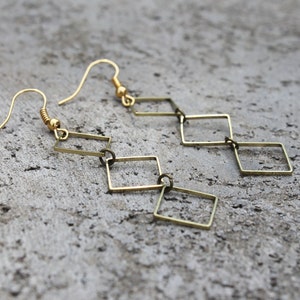 May include: Gold tone dangle earrings with a chain of connected square shapes.