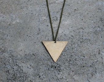 Peut inclure: Un collier avec un pendentif en forme de triangle doré sur une chaîne. Le pendentif est une forme géométrique simple avec une surface lisse.