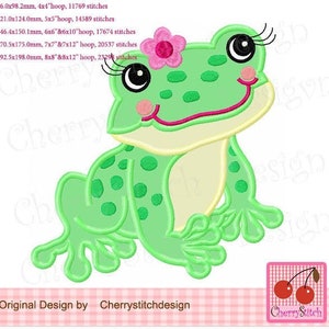 May include: Green frog embroidery design with a pink flower on its head. The frog is sitting with its legs crossed and has a big smile on its face. The design is available in multiple sizes.