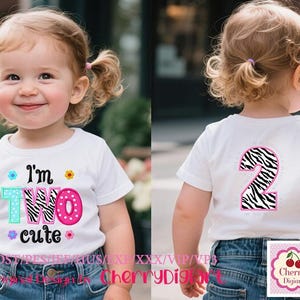May include: A white t-shirt with the text "I'm TWO cute" in colorful letters, worn by a young child. The number "2" with a zebra print is on the back of the shirt. The child is wearing blue denim jeans.