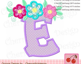 May include: Purple letter E with a dotted background and a floral design above it. The flowers are pink, blue, and green. The text "Original Design by Cherrystitchdesign" is below the letter.