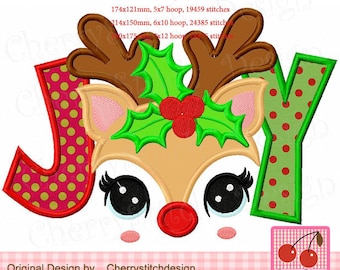 May include: A machine embroidery design featuring a reindeer face with antlers, holly, and the word "JOY". The letters are red and green with polka dots. The design includes the text "Original Design by Cherrystitchdesign".