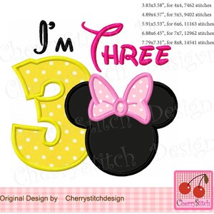 Puede incluir: Número tres amarillo con lunares blancos, un lazo rosa y orejas de Mickey Mouse negras. El texto "I'M THREE" está por encima del número. La imagen es para bordado.