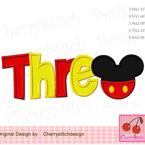 May include: Red and yellow embroidered applique of the word "Three" with a black and red Mickey Mouse head to the right. The applique is on a white background.