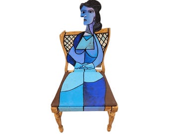 Könnte beinhalten: Ein Holzstuhl mit einem blauen und braunen Farbmuster. Der Stuhl ist mit einem stilisierten Bild einer Frau bemalt, die auf dem Stuhl sitzt. Die Frau ist im kubistischen Stil mit geometrischen Formen und Farben gemalt.
