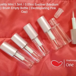 Puede incluir: Seis botellas de plástico transparente con tapas rosas y aplicadores blancos. Las botellas son de 1,5 ml o 0,05 oz y están etiquetadas como delineador de ojos. Las botellas están sobre una superficie roja. High Quality Mini 1.5ml / 0.05oz Eyeliner (Medium Thick) Brush Empty Bottle (Electroplating Pink Cap)