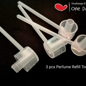 Könnte beinhalten: Drei transparente Plastik-Parfüm-Nachfüllwerkzeuge mit langen, dünnen Röhrchen. Die Werkzeuge sind zum Umfüllen von Parfüm von einer Flasche in eine andere bestimmt. Der Text "3 pcs Perfume Refill Tool" ist unter den Werkzeugen aufgedruckt.