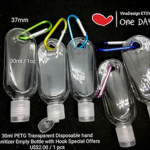 May include: Five clear plastic 30 ml / 1 oz hand sanitizer bottles with attached metal hooks. The bottles are 103 mm tall and 37 mm wide. The bottles have white caps and are arranged in a row on a dark surface. The text "One Day" is visible in the background.