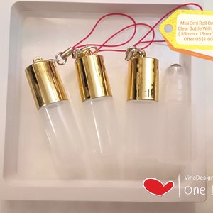 Op de afbeelding: Drie 3 ml roll-on glazen flesjes met gouden dopjes en een ophanglus. De flesjes zijn helder en meten 55 mm x 15 mm. Mini 3ml Roll On Empty Clear Bottle With Hanging (55mm x 15mm) Special Offer US$1.00 / pcs