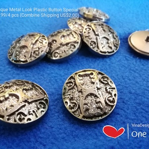 Könnte beinhalten: Nahaufnahme von acht silberfarbenen Kunststoffknöpfen mit einem dekorativen Design. Die Knöpfe haben einen Durchmesser von 25 mm und eine strukturierte, antike Metall-Optik.