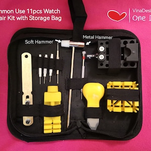 May include: A black zipped case with a handle, containing a watch repair kit with 11 pieces. The kit includes a metal hammer, a soft hammer, a case opener, a spring bar tool, a set of screwdrivers, and other tools. The case is labelled "Common Use 11pcs Watch Repair Kit with Storage Bag".