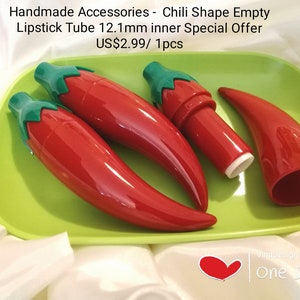 Op de afbeelding: Drie lege lippenstiftbuisjes in de vorm van rode pepers met groene toppen. De buisjes liggen op een groene dienblad. De tekst "Handmade Accessories - Chili Shape Empty Lipstick Tube 12.1mm inner Special Offer US$2.99/1pcs" is zichtbaar in de afbeelding.