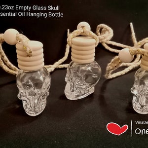 May include: Three clear glass skull-shaped bottles with wooden stoppers and a beige string hanging from each. The bottles are 7 ml or 0.23 oz in size. The bottles are empty and can be used for essential oils.