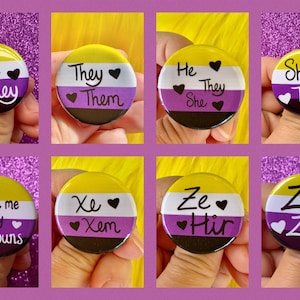 Puede incluir: Seis botones redondos con los colores de la bandera del orgullo no binario. Cada botón tiene un conjunto diferente de pronombres escritos en él, incluyendo "He They She", "They Them", "Ask me my Pronouns", "Xe Xem", "Ze Hir" y "Ze Zem".