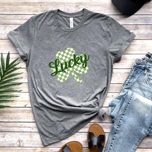 May include: A gray t-shirt with a green and white checkered shamrock and the word "Lucky" in green text.