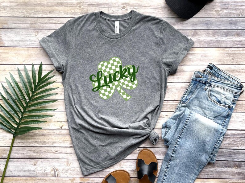 May include: A gray t-shirt with a green and white checkered shamrock and the word "Lucky" in green text.