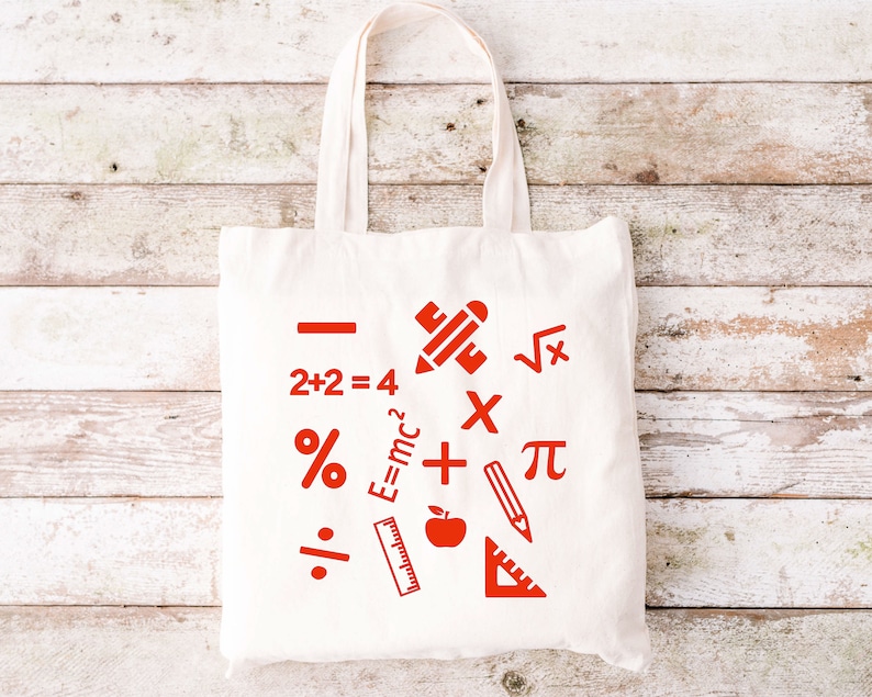 May include: White canvas tote bag with red mathematical symbols and equations, including a plus sign, minus sign, multiplication sign, division sign, percentage sign, pi symbol, square root symbol, and the equation E=mc2. The bag also features a red pencil, ruler, and apple.