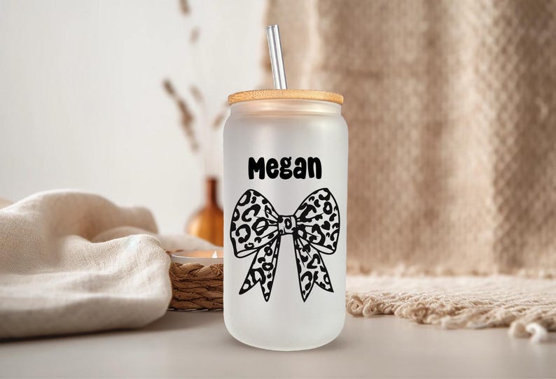 Pu&ograve; includere: Un bicchiere di vetro bianco smerigliato con un coperchio in bamb&ugrave; e un fiocco con stampa leopardata in bianco e nero. Sul bicchiere &egrave; scritto il nome "Megan".