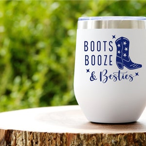 May include: White stainless steel wine tumbler with a blue graphic of a cowboy boot and the text "Boots Booze & Besties".