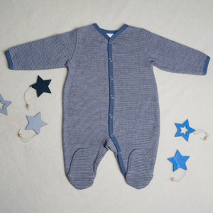 May include: A blue and white striped baby onesie with long sleeves and popper fastenings. The onesie has a contrasting blue trim around the neckline, cuffs, and legs.