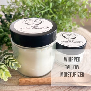 May include: Two glass jars of whipped tallow moisturizer with black lids. The jars are on a wooden surface with a wooden spoon. The label on the jar reads "Whipped Tallow Moisturizer".