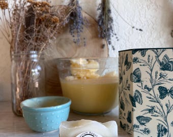 May include: A bar of white soap with a brown label that reads "Fat Bottom Beauty Co. Tallow Soap" with a small illustration of a sheep. The soap is sitting on a light gray surface.