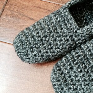 May include: A pair of gray crocheted slippers. The slippers are made with a simple stitch and have a soft, cozy look.