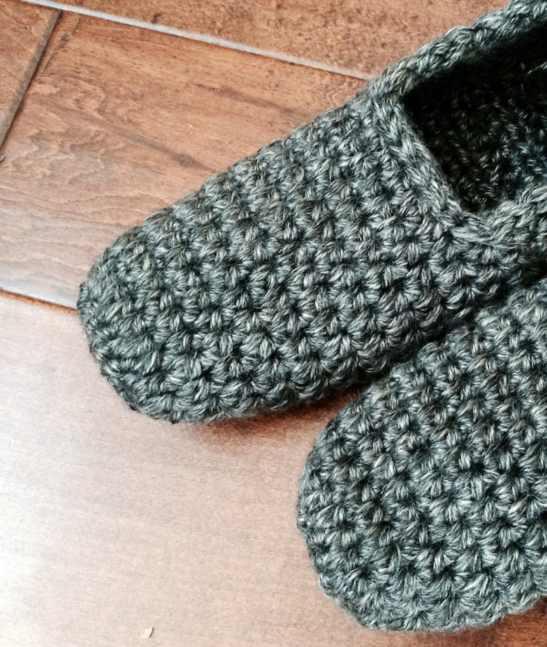 May include: A pair of gray crocheted slippers. The slippers are made with a simple stitch and have a soft, cozy look.