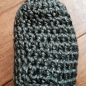 May include: Close-up of a gray and white crocheted slipper. The slipper is made with a textured stitch pattern.