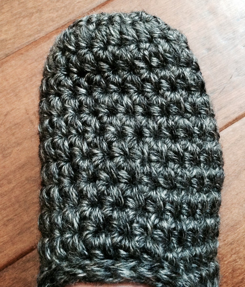 May include: Close-up of a gray and white crocheted slipper. The slipper is made with a textured stitch pattern.