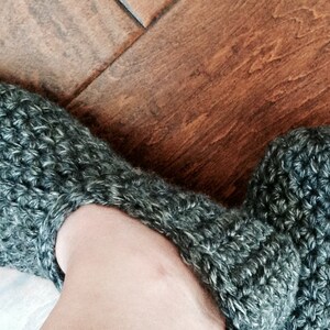 May include: A pair of gray crocheted slippers with a fuzzy texture.