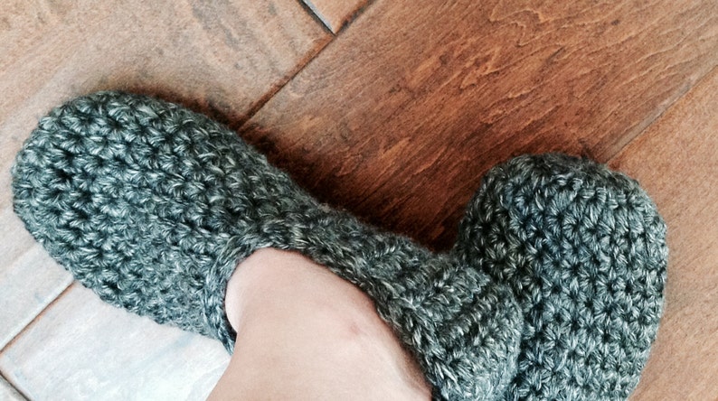May include: A pair of gray crocheted slippers with a fuzzy texture.