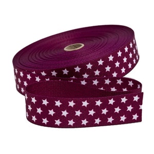 Puede incluir: Un rollo de cinta color burdeos con un patrón de estrellas blancas.