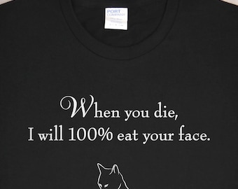 May include: Black t-shirt with white text that reads "When you die, I will 100% eat your face. With love." and a white outline of a cat licking its paw.