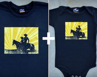 Può includere: Una maglietta nera e un body nero per neonato con un design a raggi di sole gialli e una silhouette di due persone a cavallo. Il testo "Sun Rise" è stampato nella parte inferiore del design.