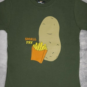 May include: A green t-shirt with a cartoon potato and french fries. The potato is smiling and holding a box of fries. The text "SMALL FRY" is printed on the shirt.