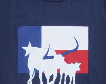 May include: A navy blue t-shirt with a white silhouette of a Texas longhorn steer and calf standing in front of a Texas flag. The text "Don't Mess With Daddy" is printed below the image.